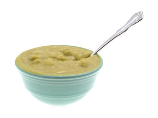 Bowl of green pea soup with a spoon side view isolated on a white background.