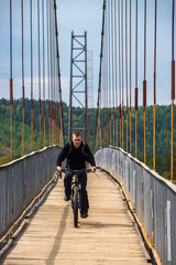 man riding bicycle across the bridge