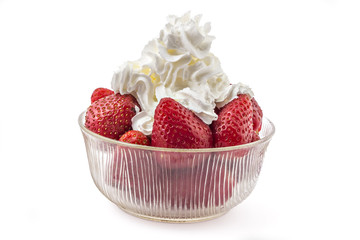 Fresh red ripe organic strawberries with whipped cream on top, in a glass bowl, isolated on white background