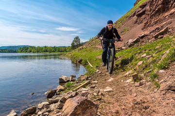Fototapeta premium cyclist rides along the rocky path near river Irkut