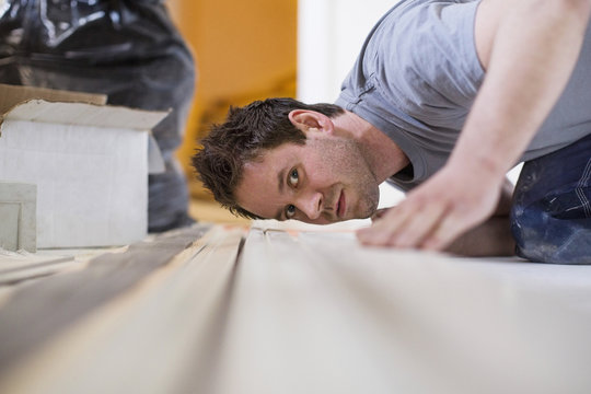 Male carpenter checking wooden plank at site
