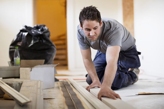 Male carpenter examining wooden plank at site