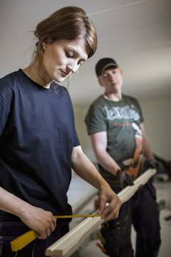 Carpenters measuring wooden plank at site