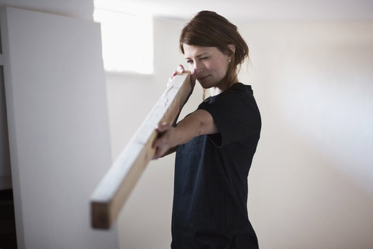 Female carpenter examining wooden plank at site