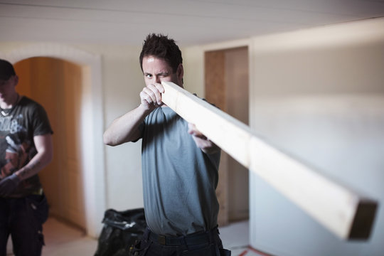 Male carpenter examining wooden plank at site
