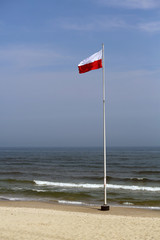 Polska flaga na maszcie nad brzegiem Bałtyku © mattajah
