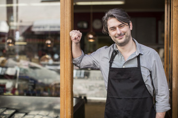 Portrait of confident salesman standing at supermarket entrance
