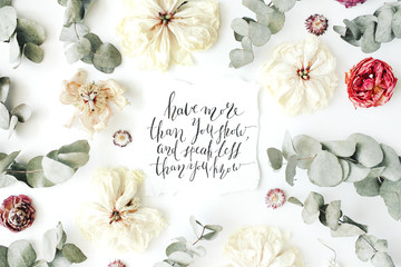quote "have more than you show and speak less than you know" written in calligraphy style on paper with pink, red roses, ranunculus, white flowers and leaves isolated on white background. Flat lay