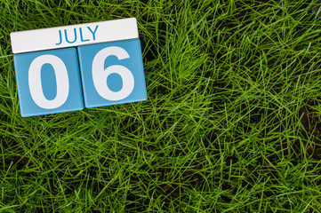 July 6th. Image of july 6 wooden color calendar on greengrass lawn background. Summer day, empty space for text