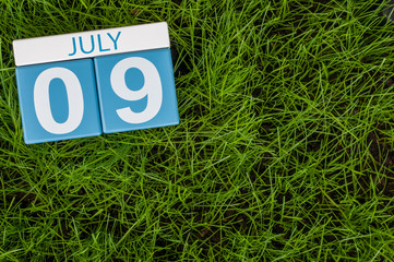 July 9th. Image of july 9 wooden color calendar on greengrass lawn background. Summer day, empty space for text