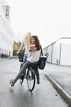 Teenage girls riding bicycle on high school campus