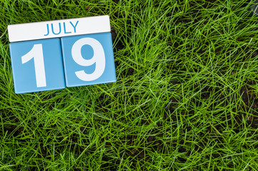 July 19th. Image of july 19 wooden color calendar on greengrass lawn background. Summer day, empty space for text
