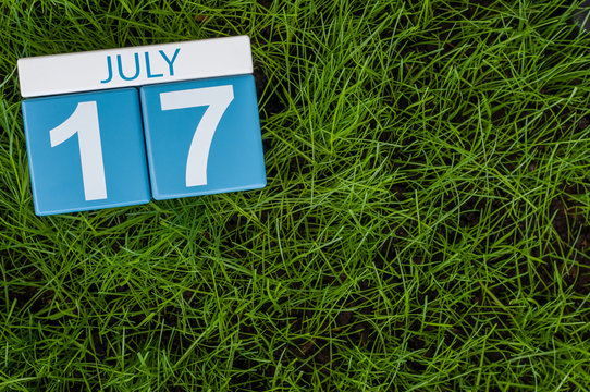 July 17th. Image of july 17 wooden color calendar on greengrass lawn background. Summer day, empty space for text