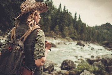 Beautiful woman hiker enjoying amazing landscapes near wild mountain river.