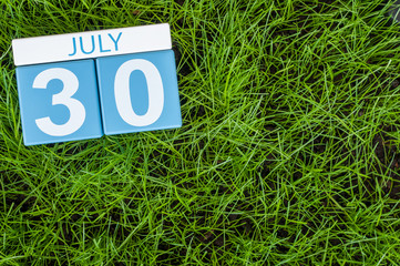 July 30th. Image of july 30 wooden color calendar on greengrass lawn background. Summer day, empty space for text