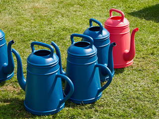 Fototapeta na wymiar Colorful watering cans on green grass