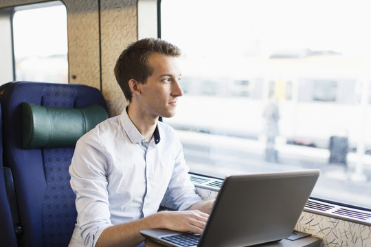 Young businessman using laptop on train
