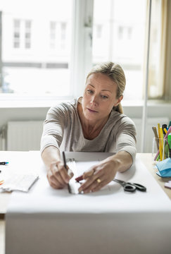Mature businesswoman drawing line using ruler on paper