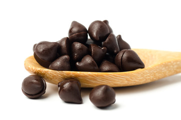Chocolate chips on wooden spoon and white background