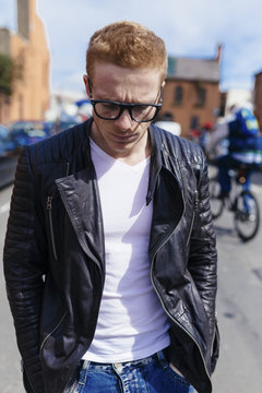 Portrait of unhappy young man wearing black glasses and leather jacket