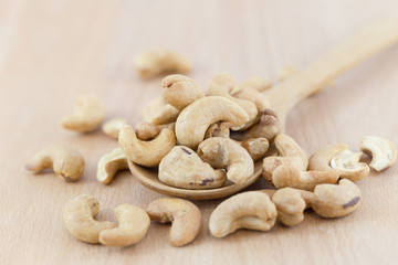 Cashew nuts in wooden spoon on wooden table