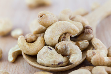 Cashew nuts in wooden spoon on wooden table