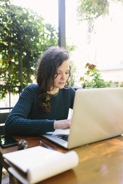 Young woman sitting on balcony using laptop