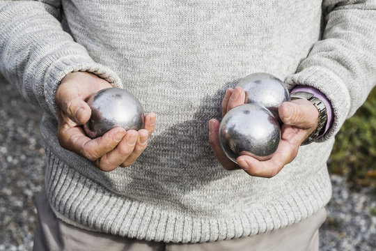 Midsection of senior man holding bocce balls outdoors
