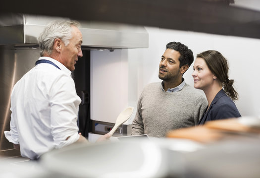 Chef talking to business people in commercial kitchen