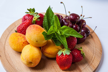 fruits and berries on a wooden cutting board