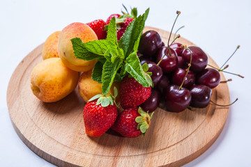 fruits and berries on a wooden cutting board