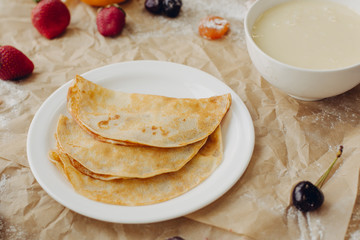 Pancakes with jam and berries on parchment background