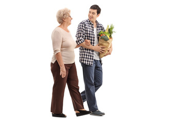 Man helping a senior lady with groceries