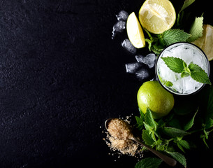 Ingredients for making mojitos (ice cubes, mint leaves, sugar and lime on dark rustic background)