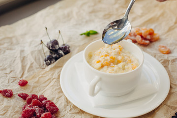 Millet porridge with pumpkin and oil spoon. Parchment background.