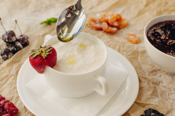 Rice porrige with strawberry and oil spoon on parchment background
