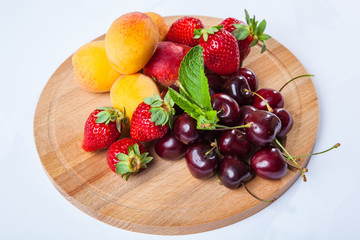 fruits and berries on a wooden cutting board