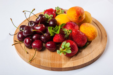 fruits and berries on a wooden cutting board