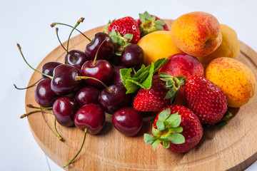fruits and berries on a wooden cutting board
