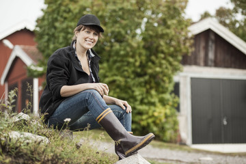 Woman in rubber boots sitting on rock