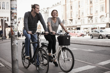 Happy couple riding bicycles on city street