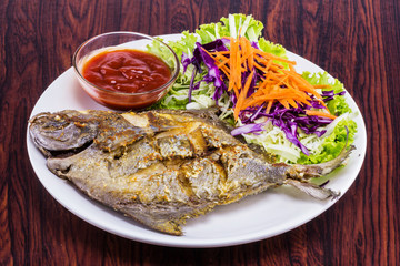 Fried fish with garlic on white plate