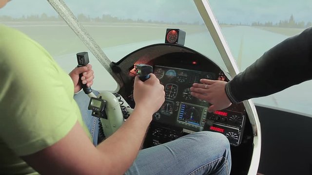 Teacher helping aviation school student control steering wheel, flight simulator