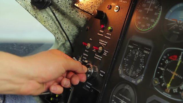 Male hand turning key to start engine, switching controls, aircraft takeoff