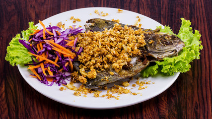 Fried fish with garlic on white plate