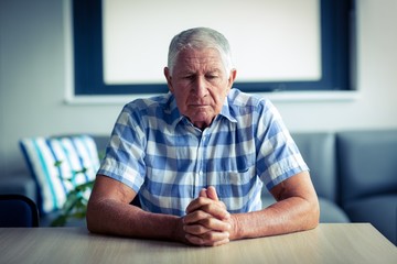 Worried senior man sitting in living room 
