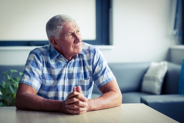 Worried senior man sitting in living room 
