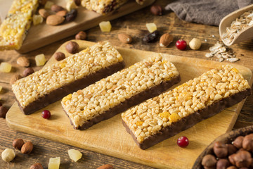 Granola bars. Healthy food: energy granola bars with cornflakes, puffed cereals and rolled oats covered in chocolate on wooden cutting board