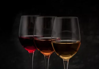 Fotobehang Red, pink and white wine in glasses on black grunge background © Rozmarina