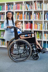 Obraz premium Happy schoolgirl standing with schoolboy on wheelchair